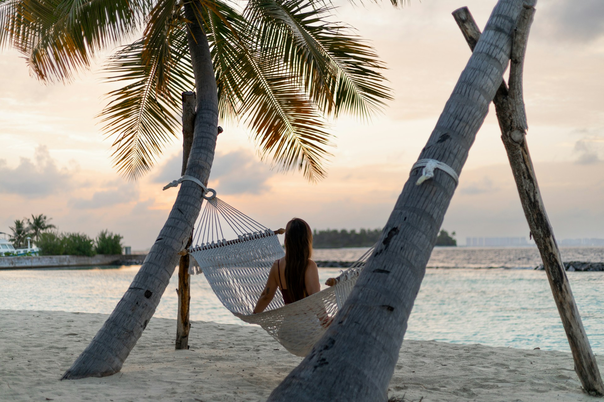 Kvinne i en hengekøye på stranda på Maldivene på kvelden ved solnedgang